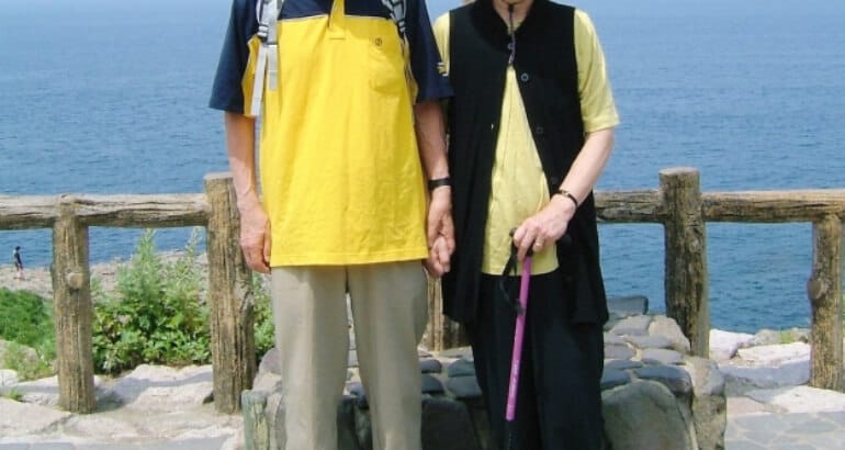 景色を背景に記念写真を撮る老夫婦